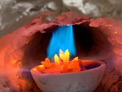 Inside a lined gas forge, blue gas (propane) heats up steel screws to orange and bright yellow hot.