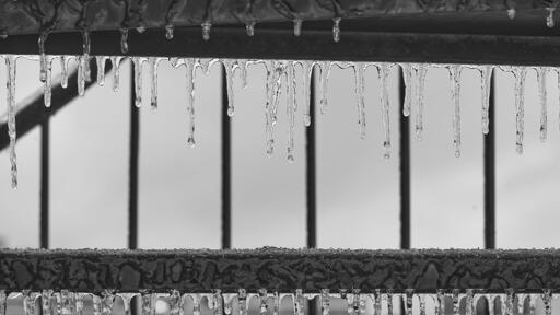 Abstract composition of icicles forming between steps of a metal staircase